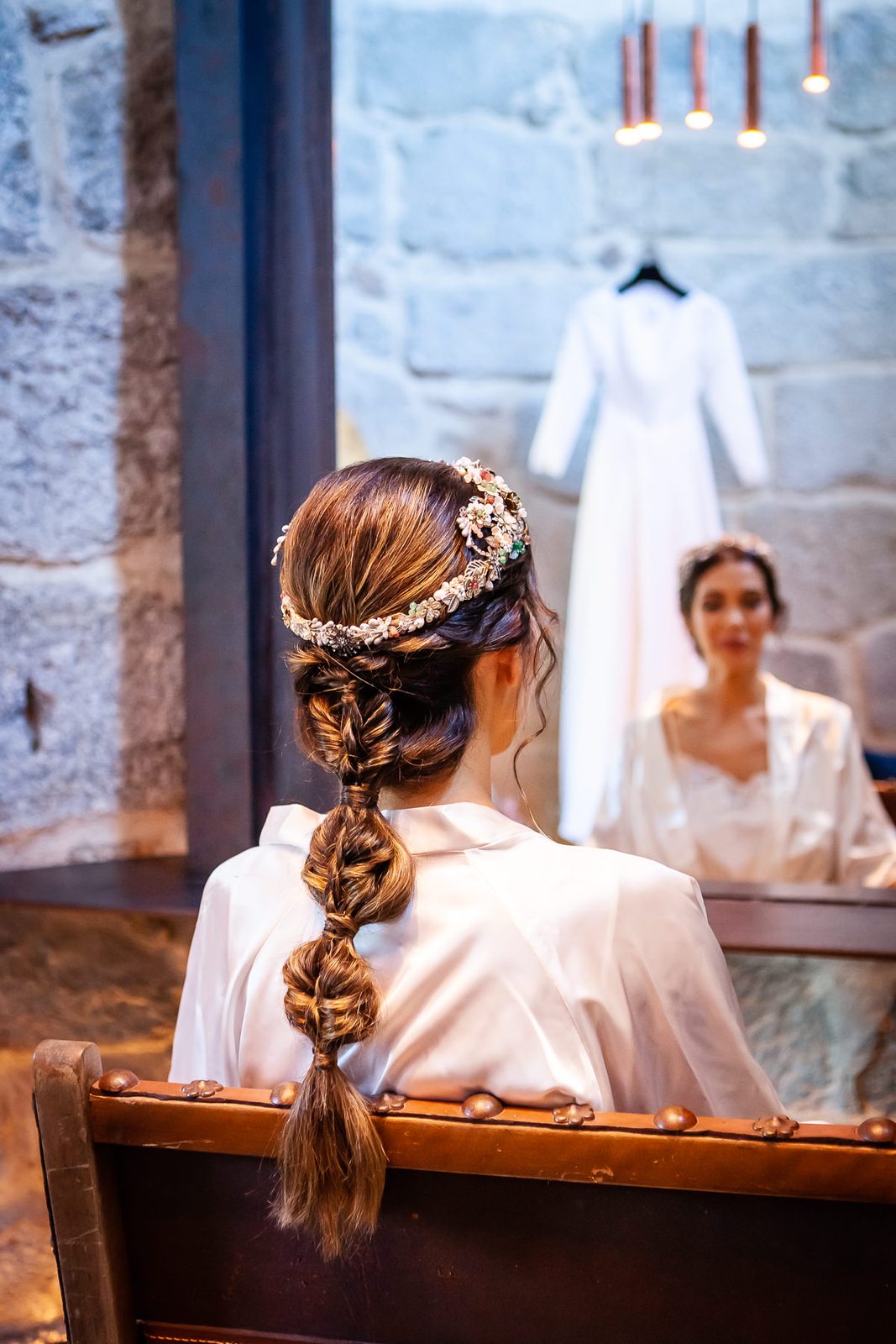 Novia frente al espejo con trenza y corona de flores