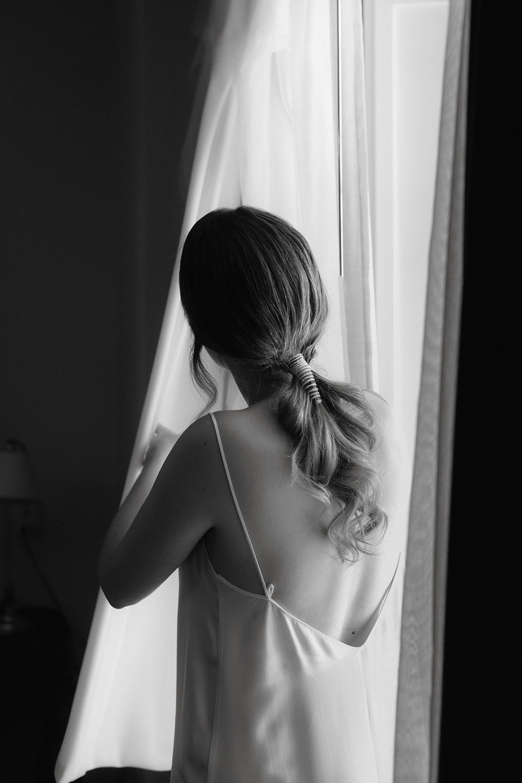 Novia en la ventana con coleta baja y joya